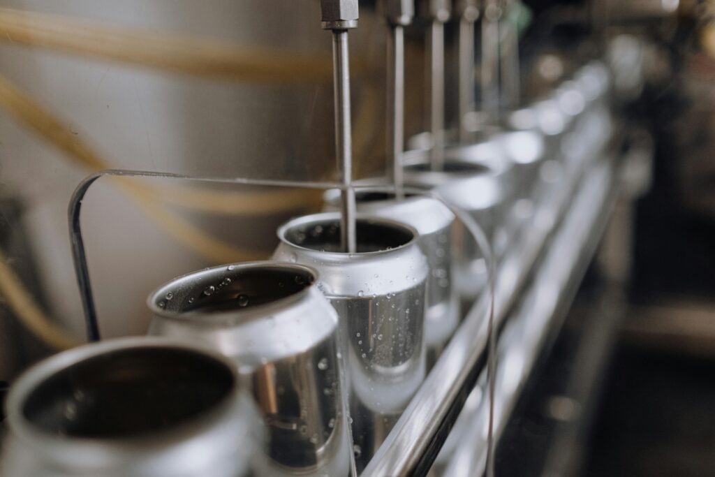 Detailed view of an industrial canning process with aluminum cans on an automatic assembly line.