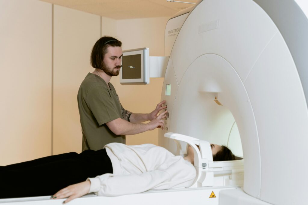 Medical technician operating MRI scanner for patient examination in healthcare setting.